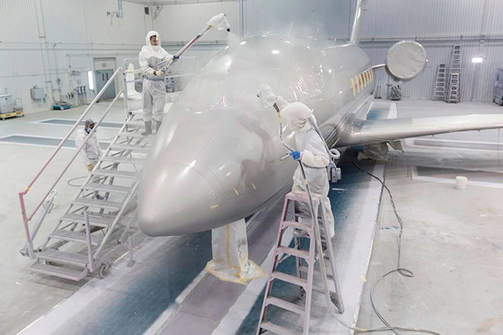 هواپیمای جت در حال رنگ‌شدن در آشیانه توسط 2 فرد