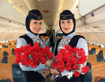 عکس دونفری سرمهمانداران هواپیمایی کاسپیین در کنار هم داخل هواپیما با دست گل رز برای دادن به مسافران